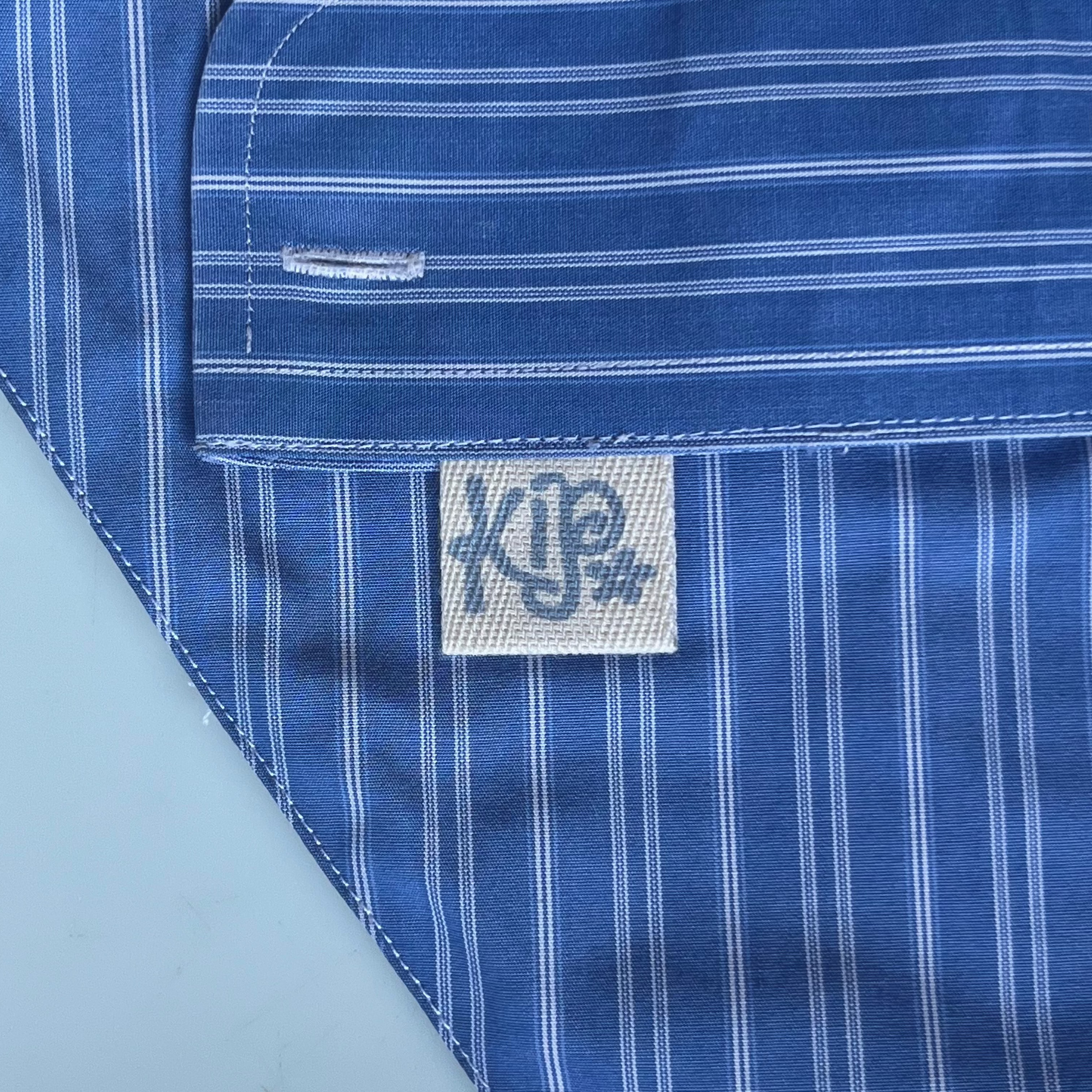 Close-up of a blue striped shirt with a brand label on a marble background